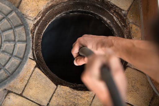 Plumber inserting drain snake into floor drain.