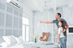 Dad with arm wrapped around his daughter showing her how the new AC system in her bedroom works