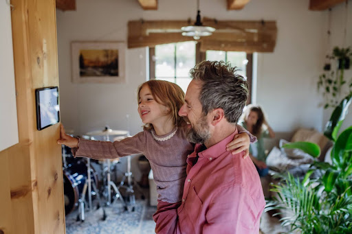 Dad holding daughter while she looks at Aeris thermostat settings.